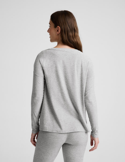 Pregnant woman wearing a gray long-sleeve top and leggings on a white background.