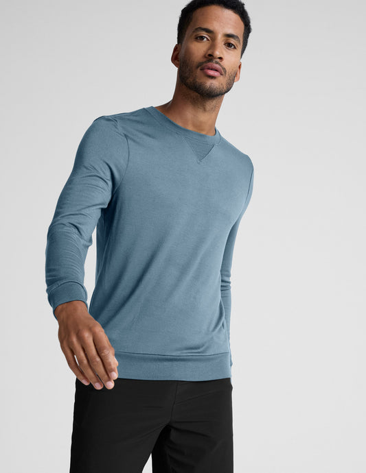 Man wearing a blue sweater and black shorts on a white background.