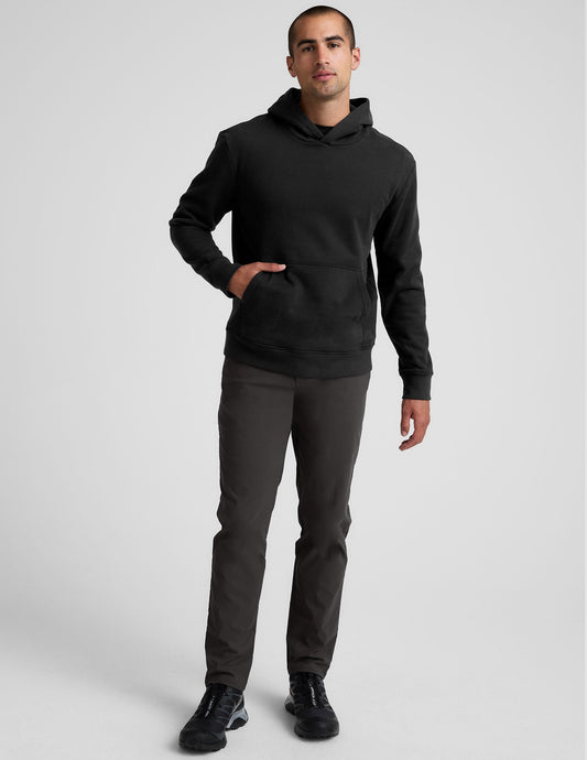 A man wears the dark grey Essential Men's Chino 30" Trouser, featuring a slim fit, straight leg, and minimalist design.