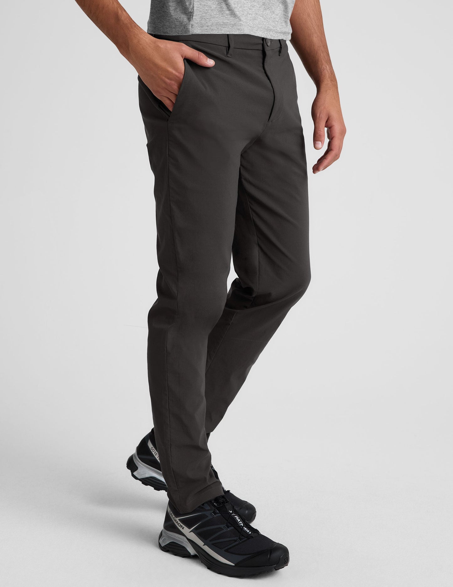 Side view of the black Essential Men's Chino 30" Trouser featuring a slim fit, side slant pockets, and belt loops on a model.