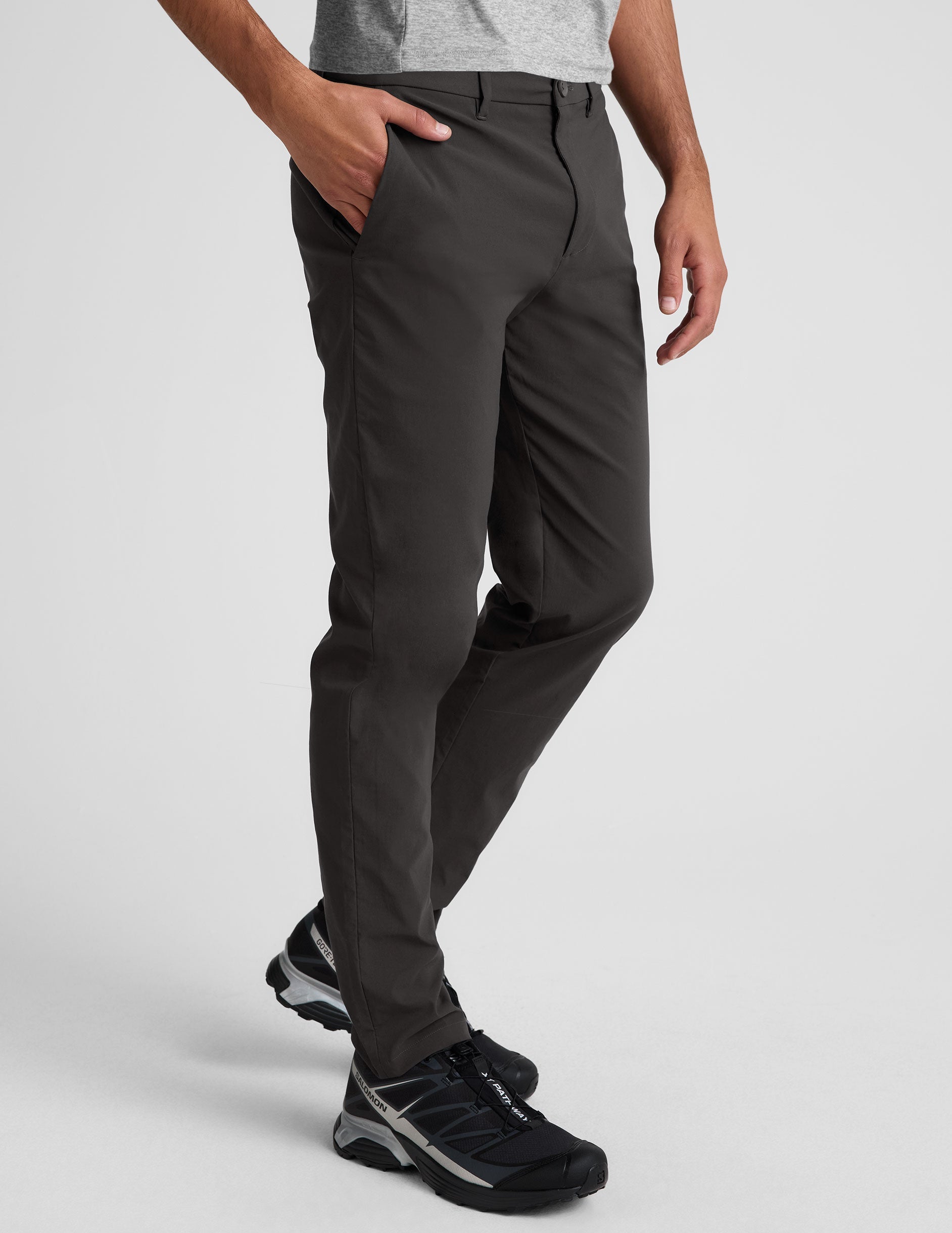 Side view of the black Essential Men's Chino 30" Trouser featuring a slim fit, side slant pockets, and belt loops on a model.
