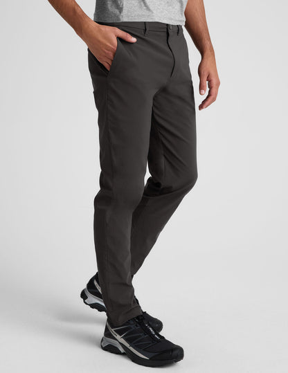 Side view of the black Essential Men's Chino 30" Trouser featuring a slim fit, side slant pockets, and belt loops on a model.