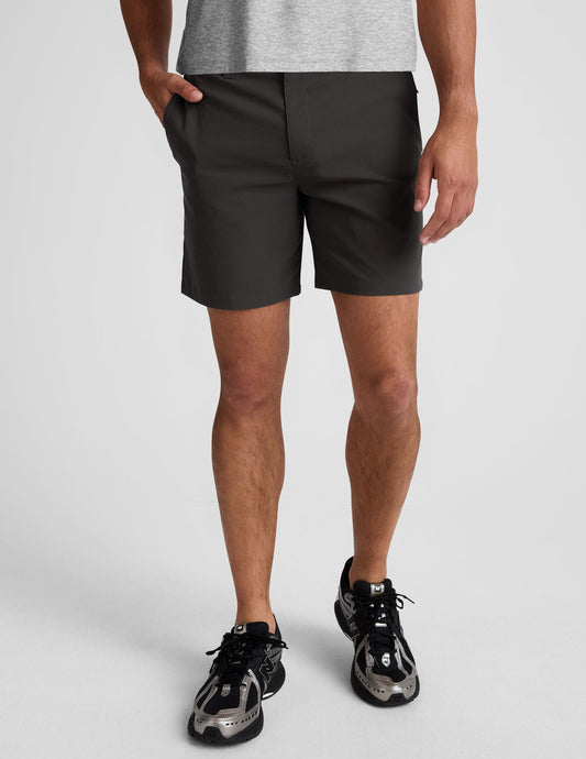 Essential Men's Chino 7" Short in dark grey, a mid-thigh tailored fit with belt loops and button fly on a standing model.