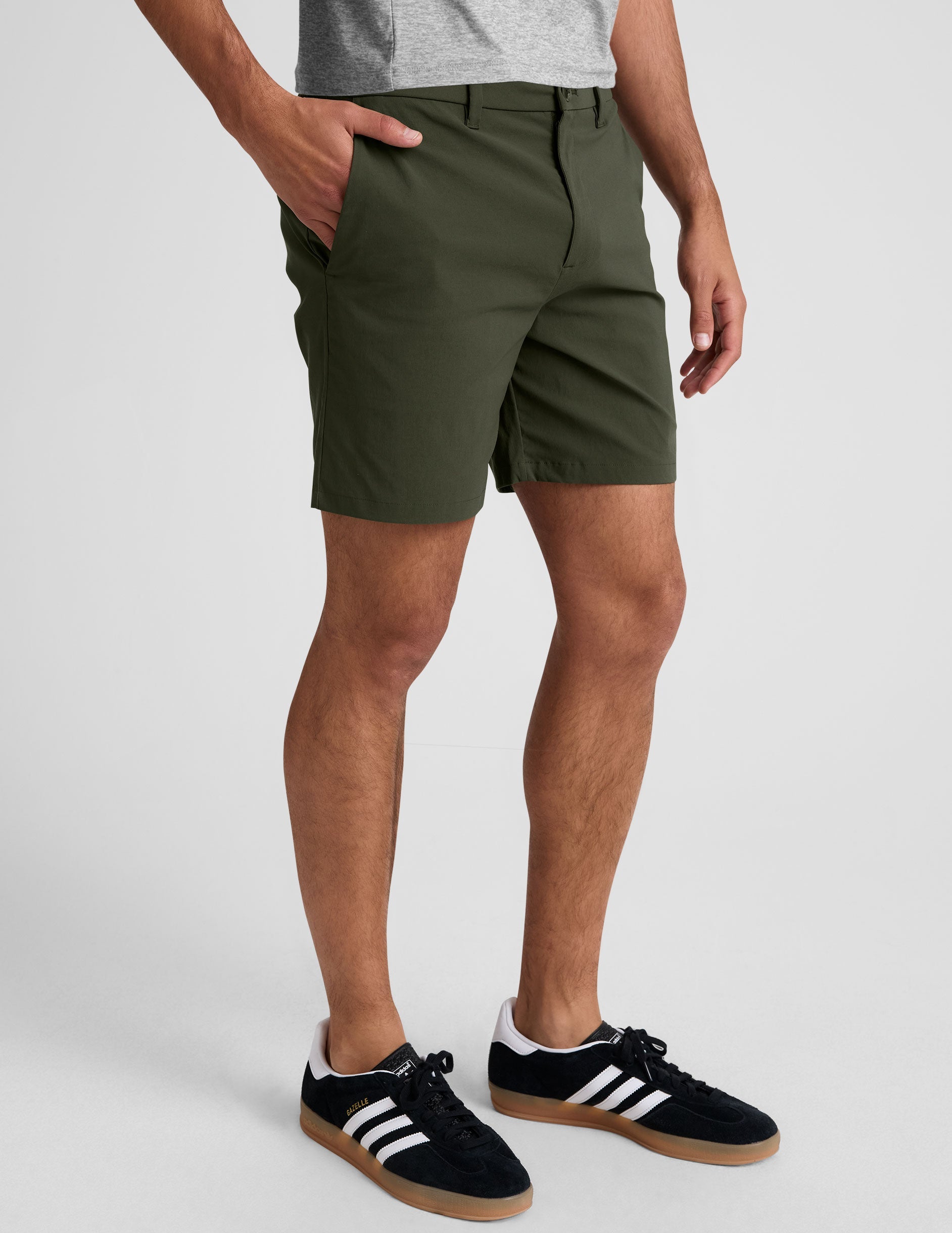 Olive green Essential Men's Chino 7" Short on a model, featuring a tailored mid-thigh length and side hand pockets.
