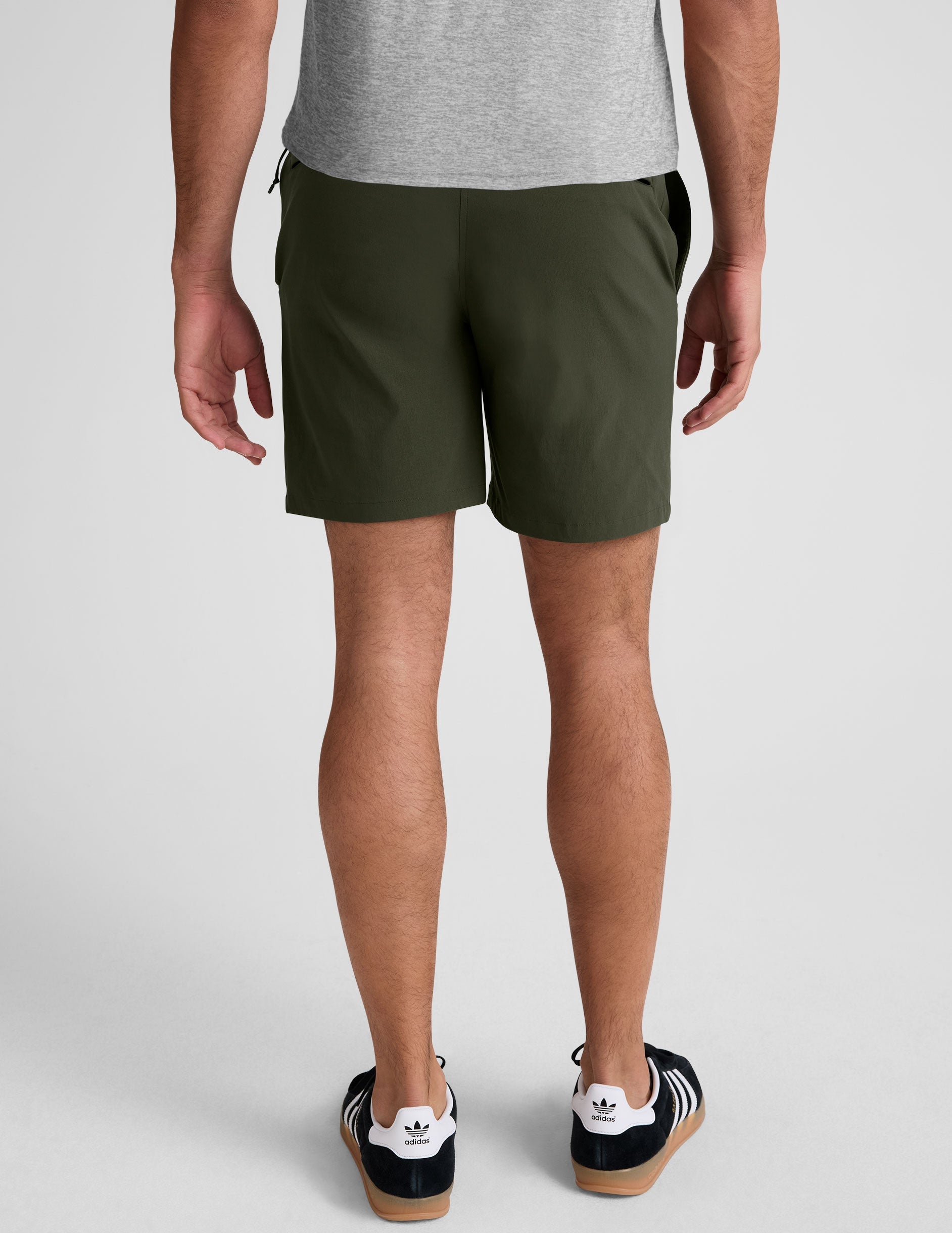 Rear view of a man wearing olive Essential Men's Chino 7" Shorts featuring belt loops and welt back pockets.