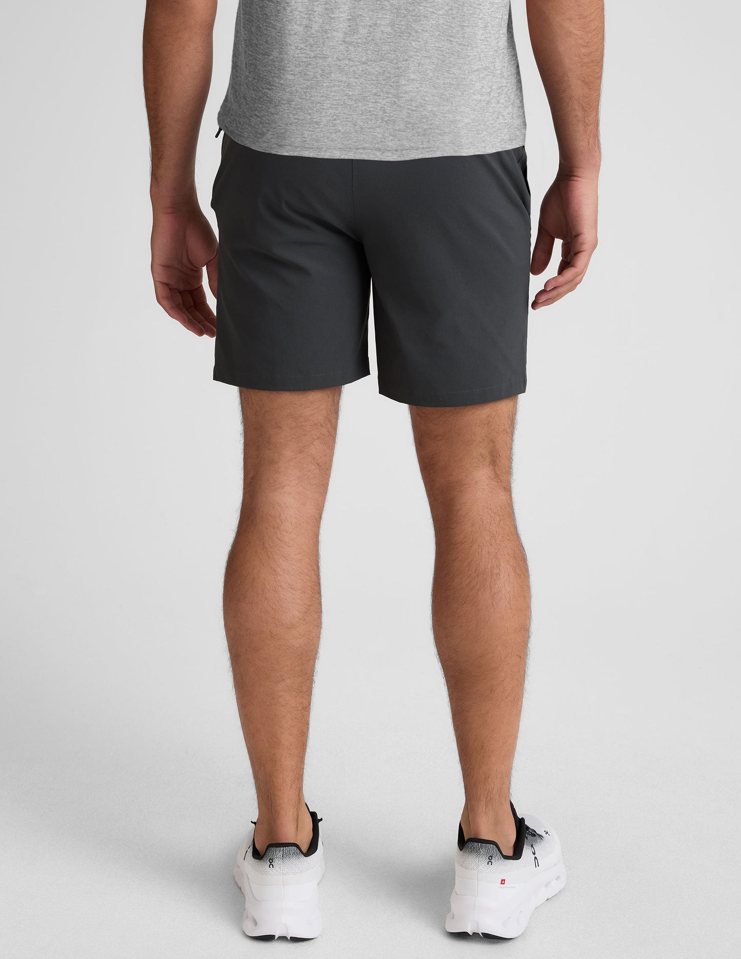 Rear view of dark gray Essential Men's Chino 7" Short on a model, featuring belt loops and two back welt pockets.