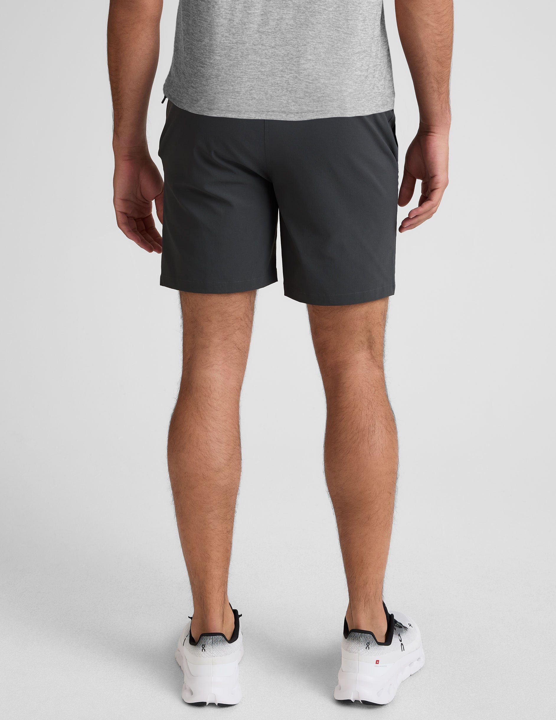 Rear view of dark gray Essential Men's Chino 7" Short on a model, featuring belt loops and two back welt pockets.
