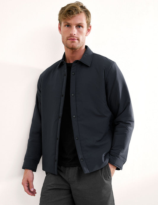 Man wearing a dark jacket over a black shirt on a white background.
