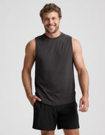 Man wearing a black sleeveless shirt and shorts on a light gray background.