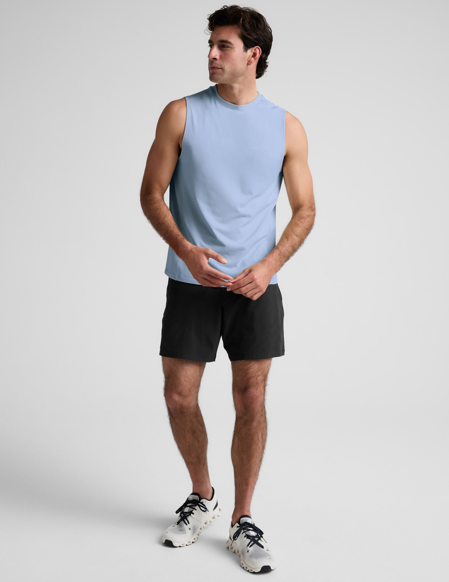 Man wearing a blue tank and black shorts against a plain background.