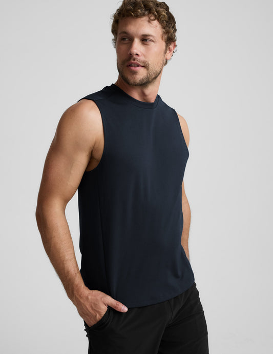 Man wearing a blue sleeveless shirt and black shorts against a light background.