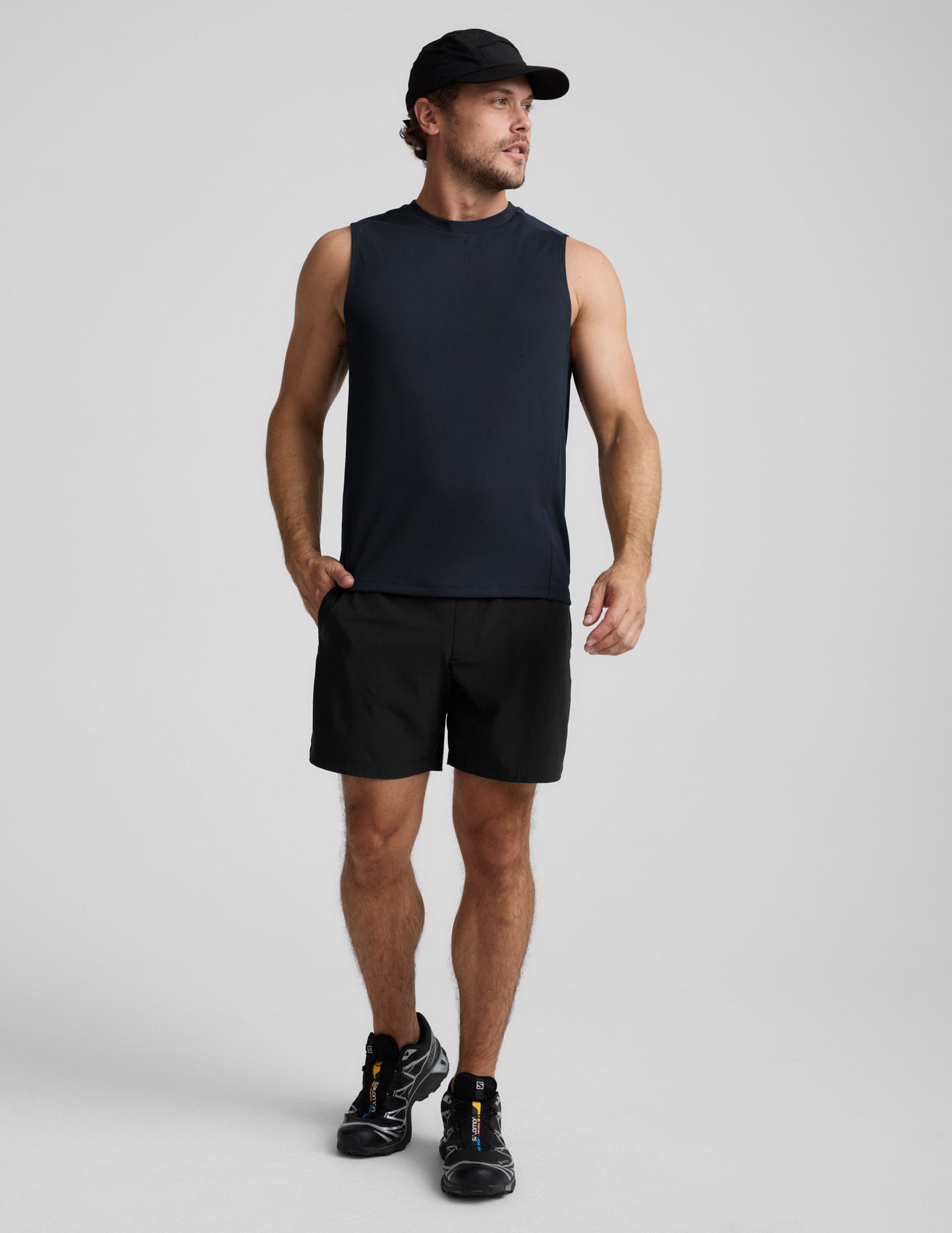 Man wearing a blue sleeveless shirt and black shorts against a light background.