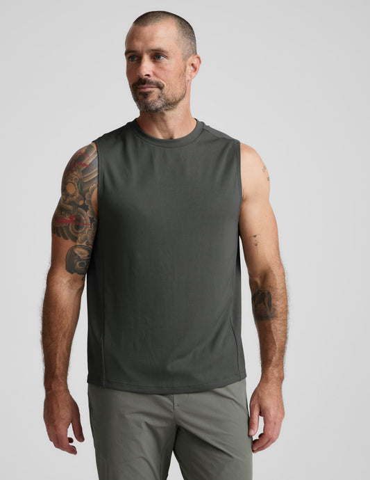 Man wearing a green tank top and shorts against a plain background.