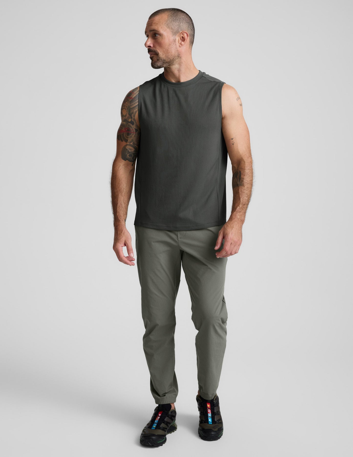 Man wearing a green tank top and shorts against a plain background.