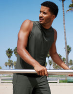 Man wearing a green tank top and shorts outdoors.