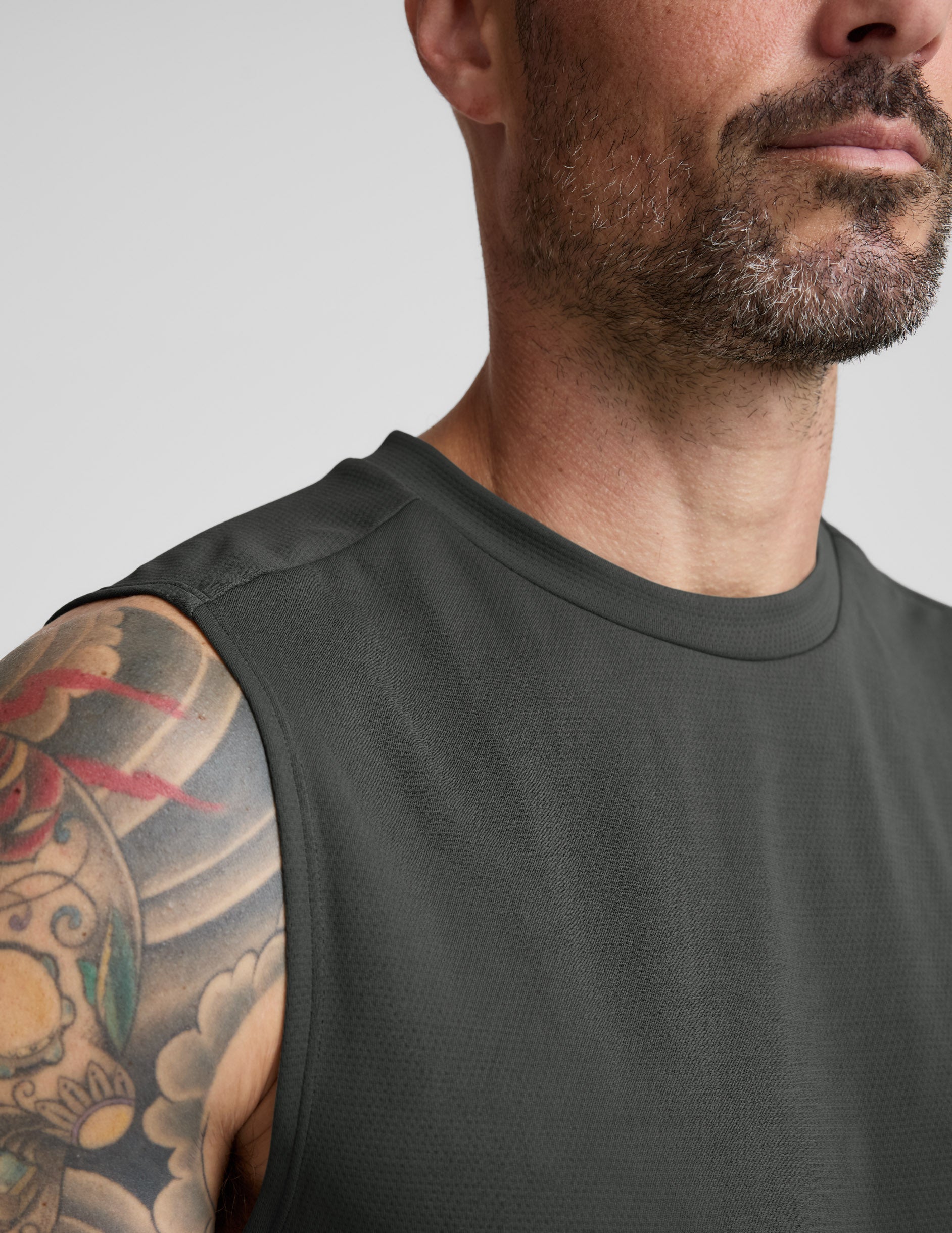 Man wearing a green tank top and shorts against a plain background.