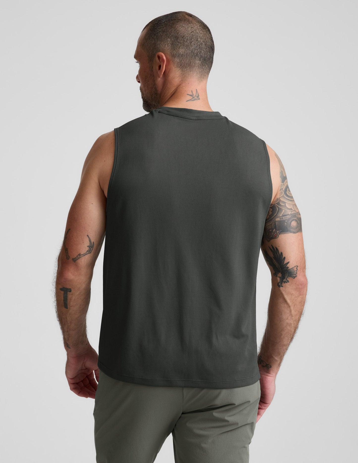 Man wearing a green tank top and shorts against a plain background.