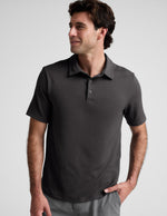 Man wearing a dark gray polo shirt against a light gray background.