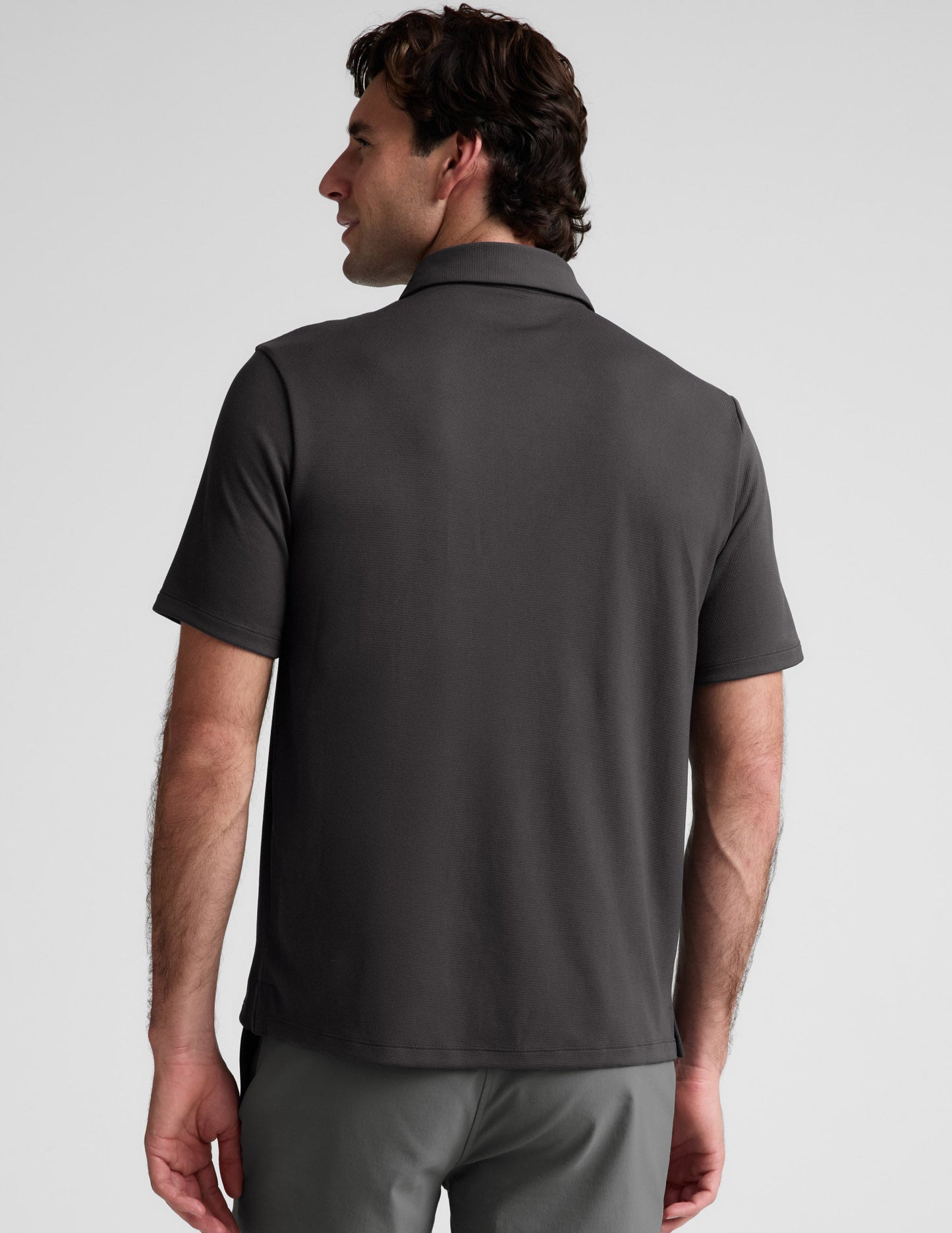Man wearing a dark gray polo shirt against a light gray background.