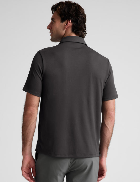 Man wearing a dark gray polo shirt against a light gray background.