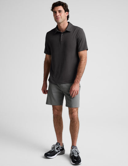Man wearing a dark gray polo shirt against a light gray background.