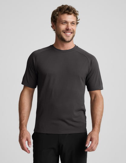 Man wearing a black athletic short sleeve top and black shorts against a plain background.