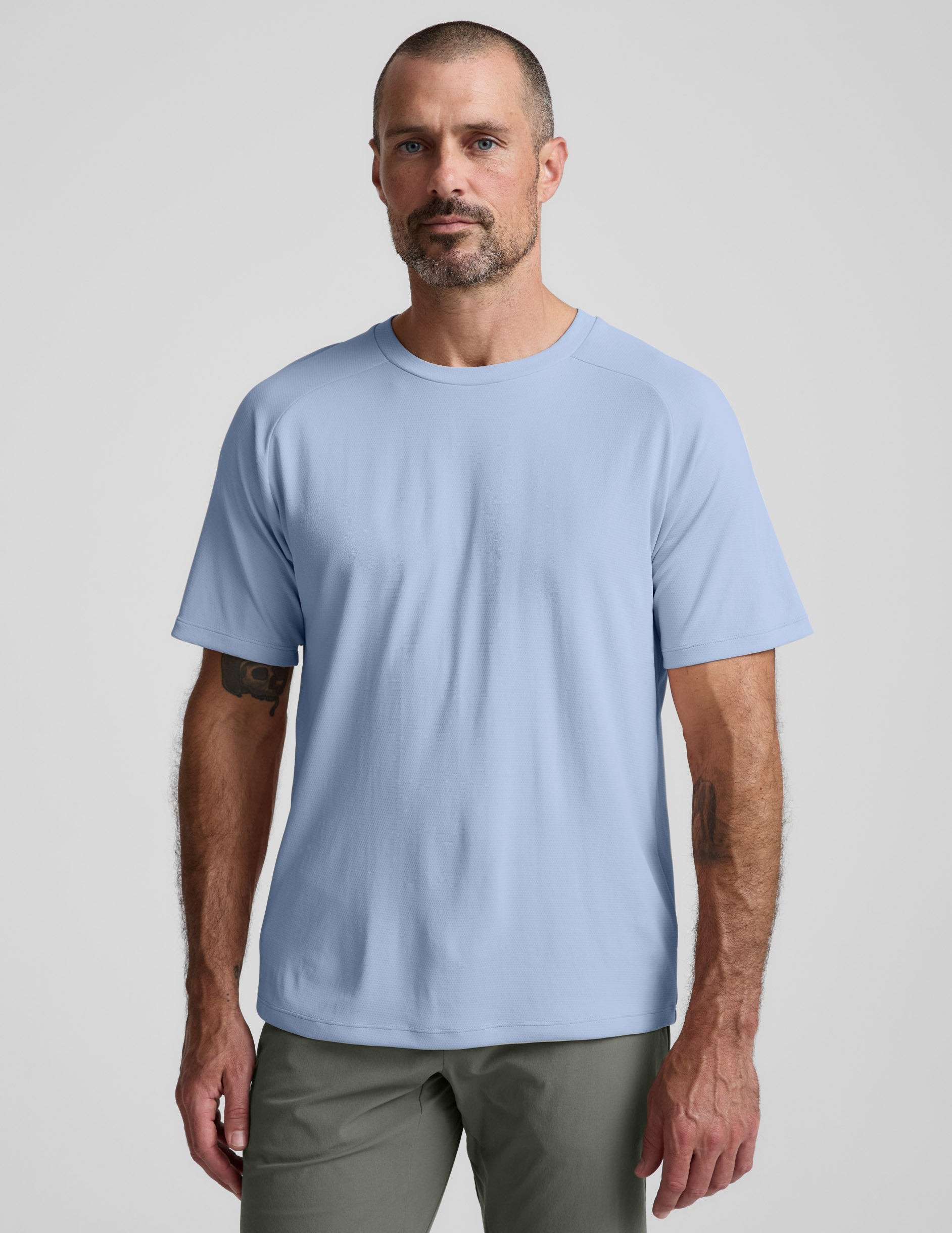 Man wearing a blue t-shirt and pants against a plain background.