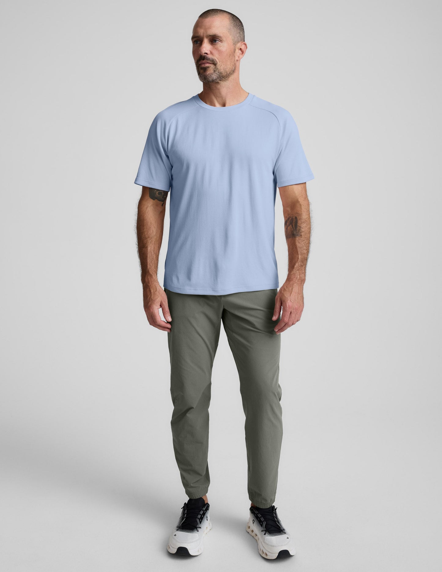 Man wearing a blue t-shirt and pants against a plain background.