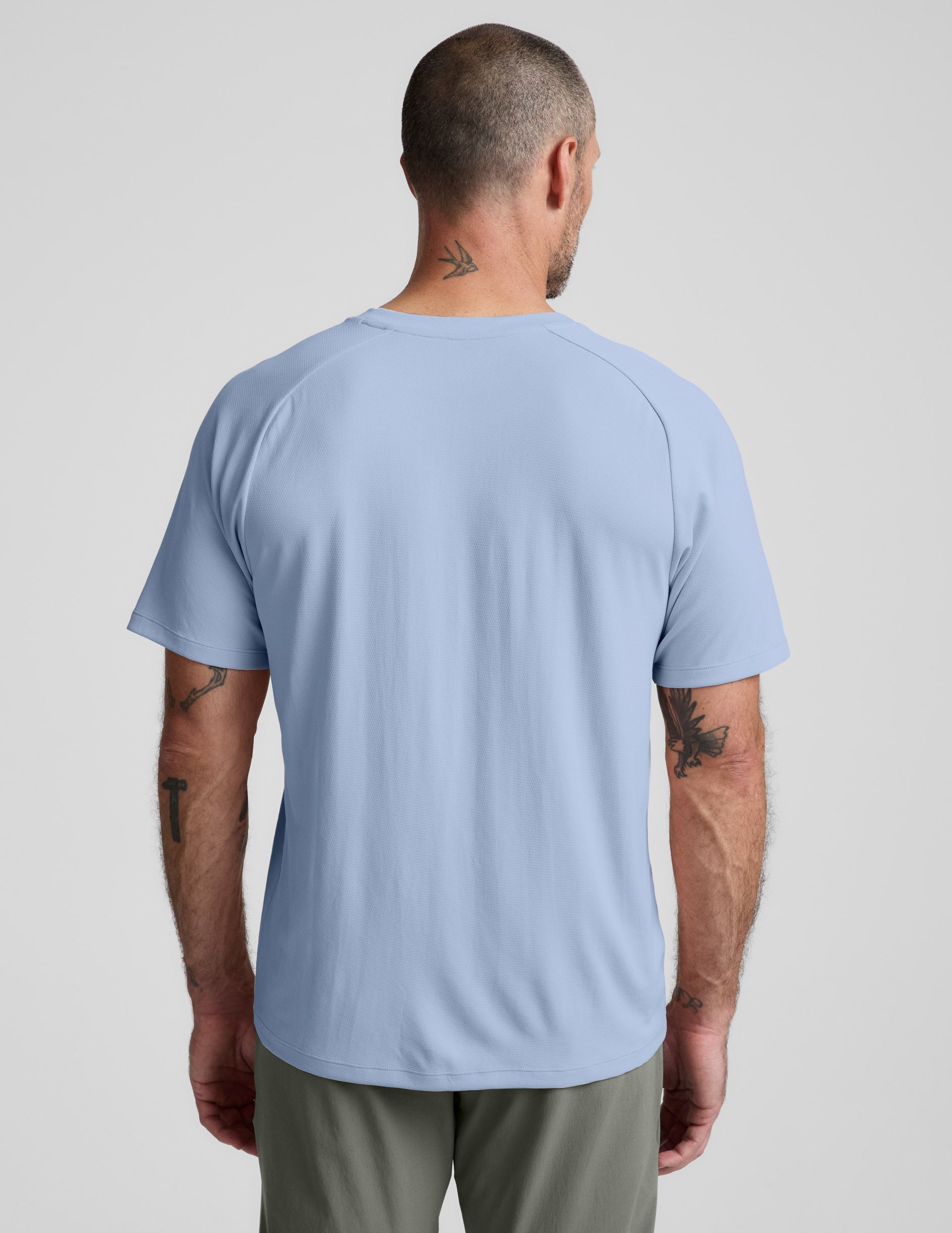 Man wearing a blue t-shirt and pants against a plain background.