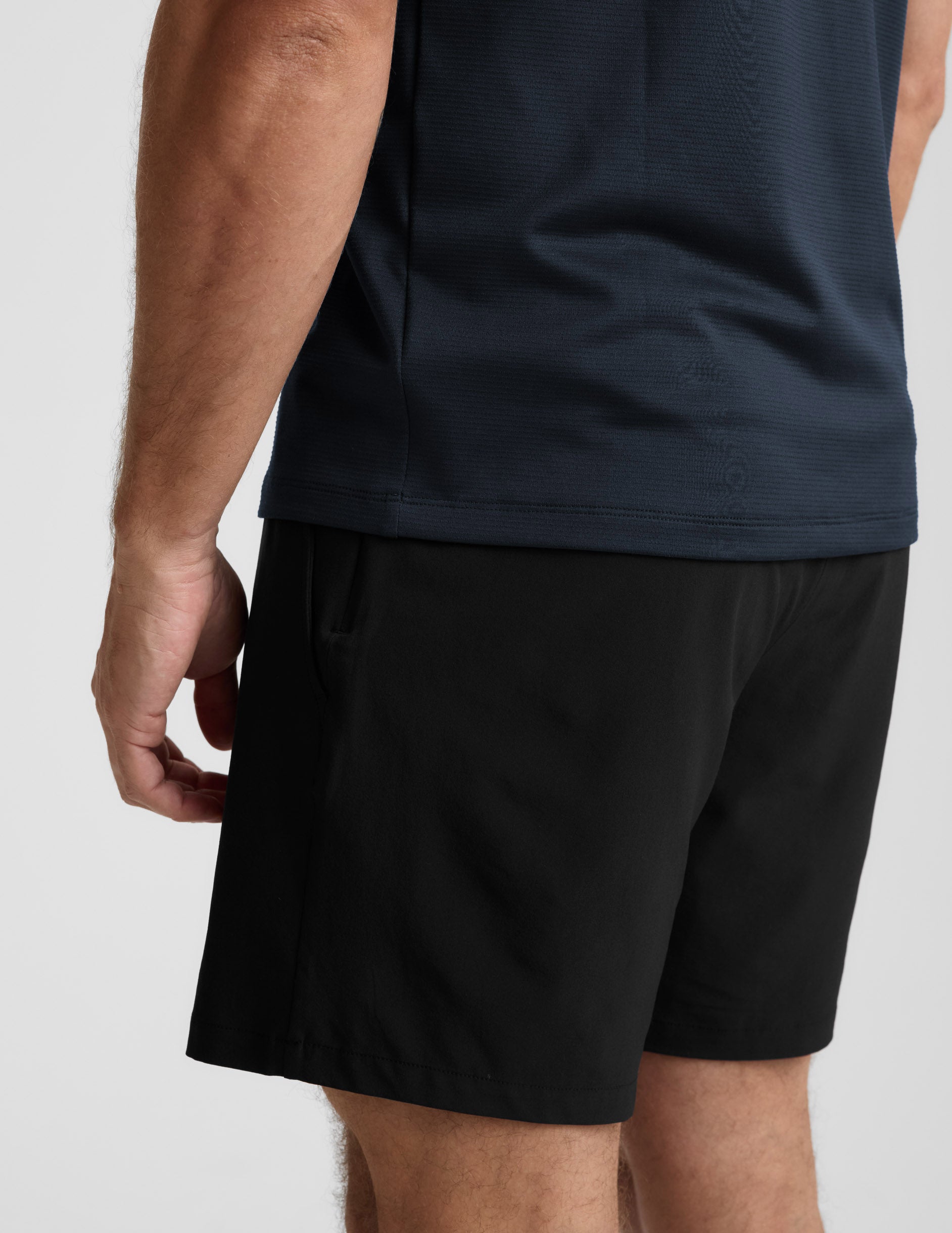 Person wearing black shorts and a dark shirt on a light gray background