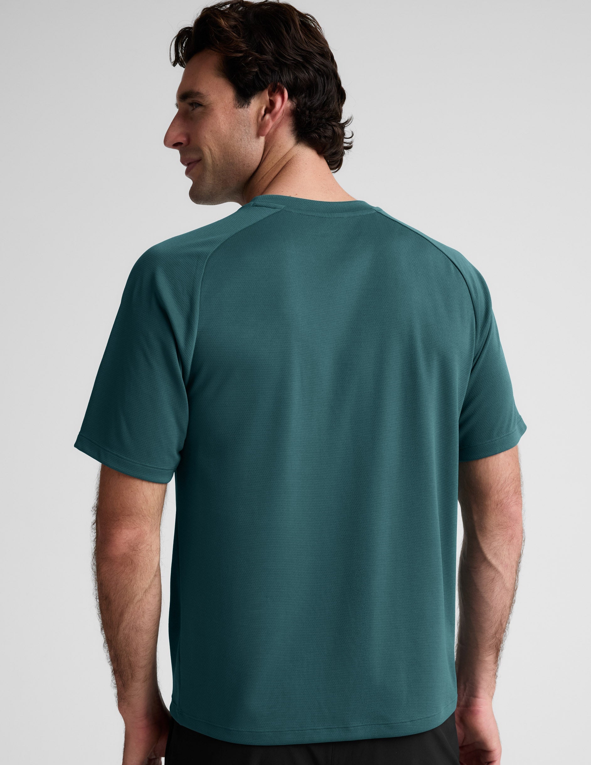 Man wearing a teal t-shirt against a plain background.