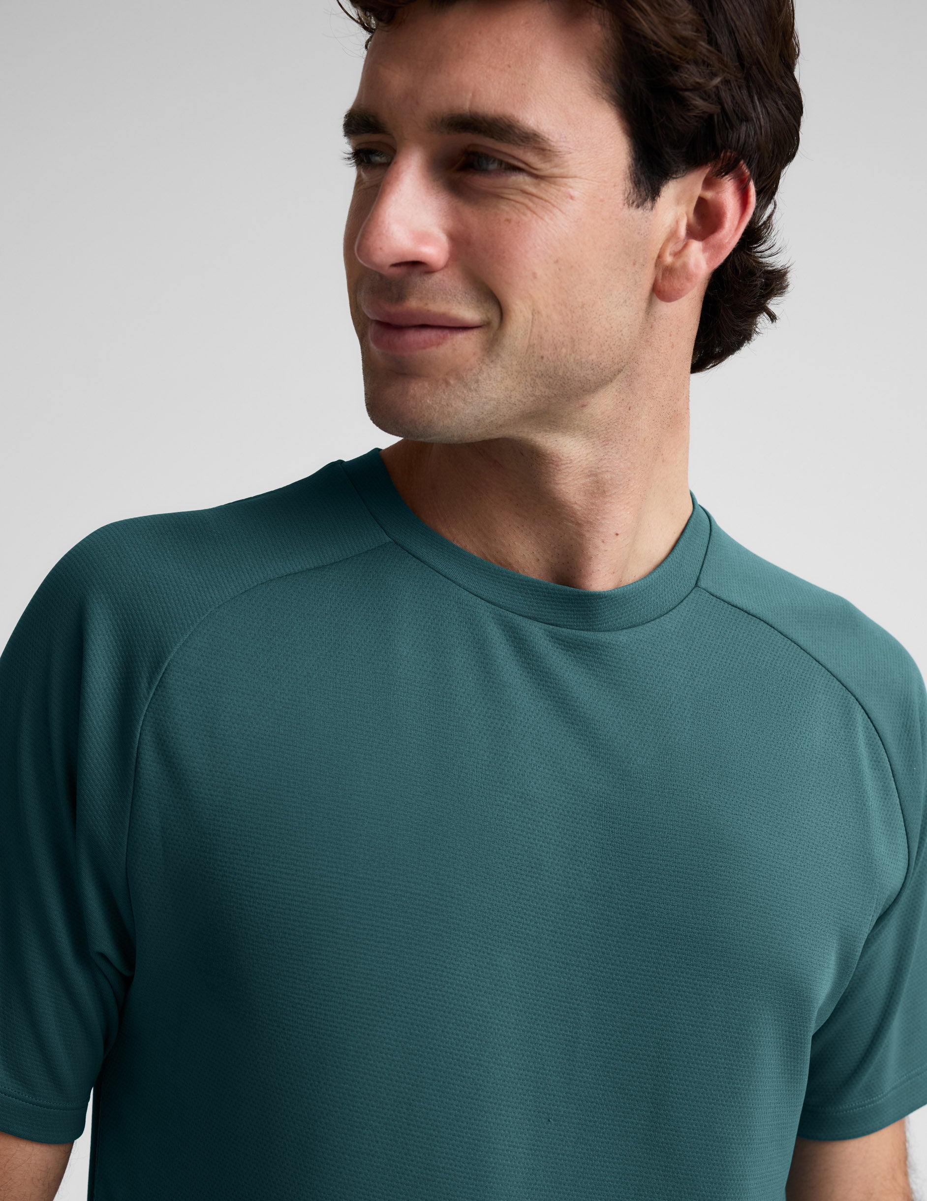 Man wearing a teal t-shirt against a plain background.
