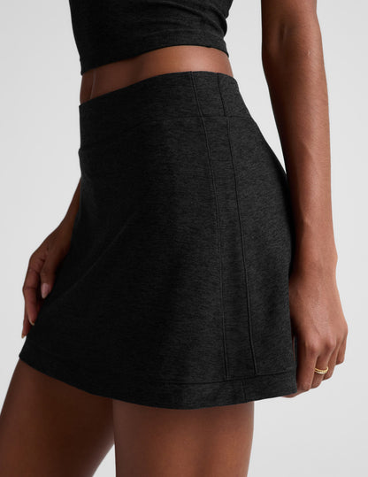 Woman wearing Black Midweight Spacedye Kickstart Skirt™ paired with a matching crop top, showing side seam details.