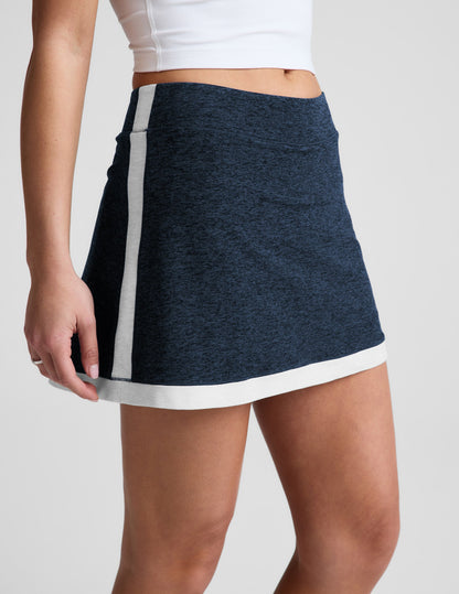 Woman wearing the navy marled Midweight Spacedye Kickstart Skirt with white trim, paired with a white cropped top.