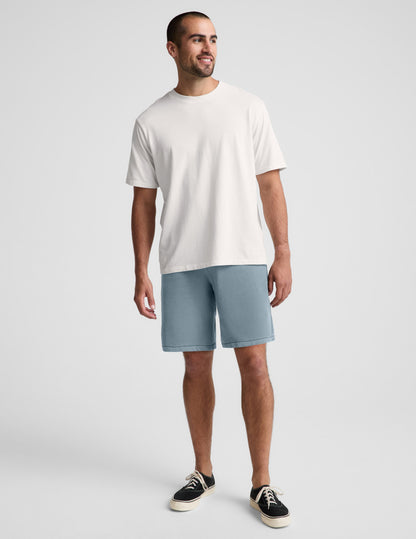 Man wearing blue Beach Washed Terry™ Men's Short paired with a white t-shirt and black sneakers.