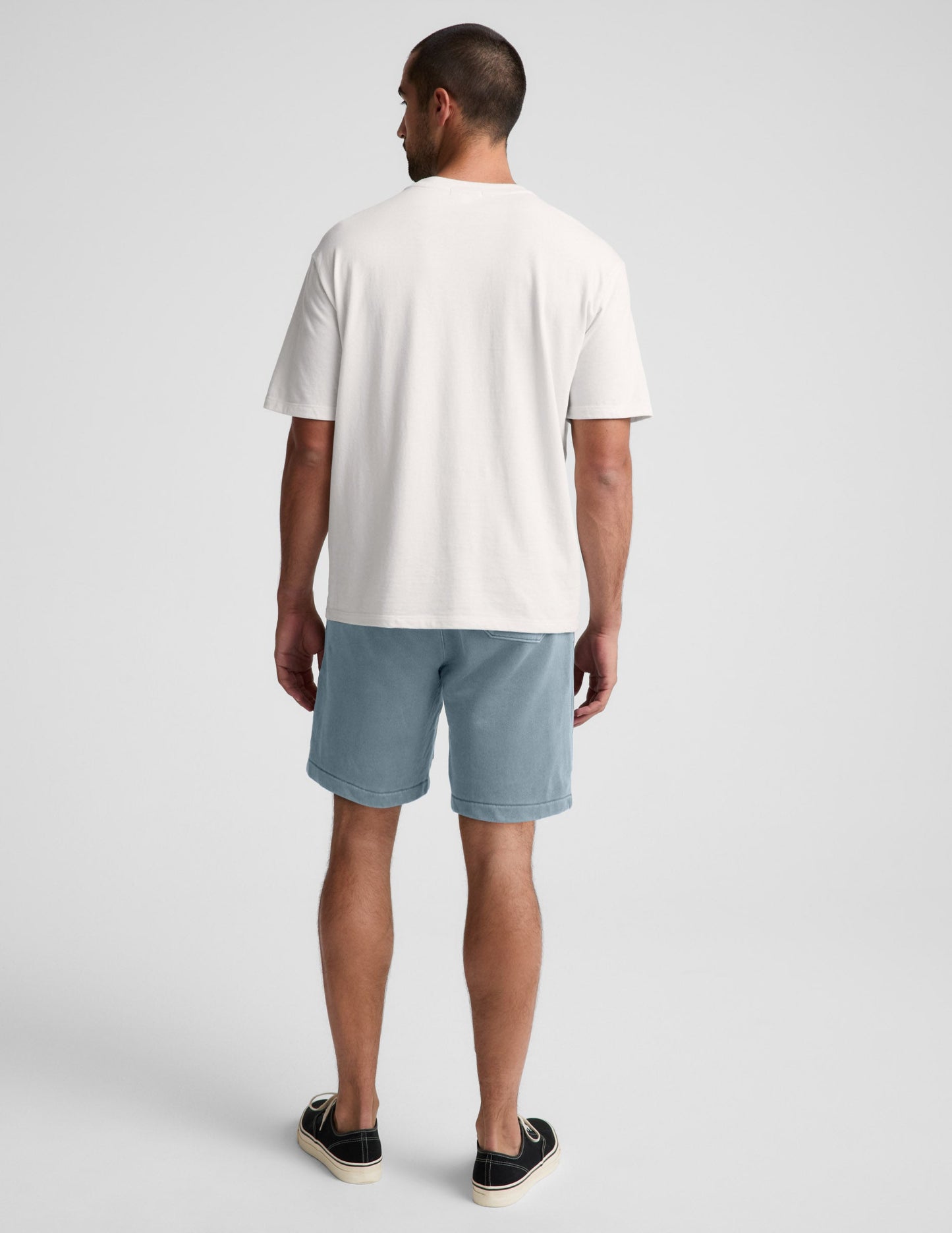 Man wearing Blue Beach Washed Terry Men's Short, rear view, paired with a white t-shirt and black sneakers.