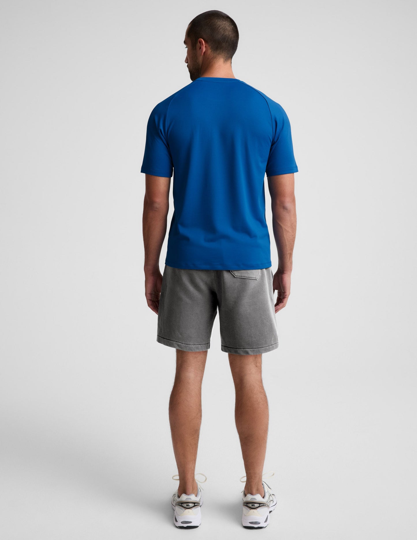 Man wearing Gray Beach Washed Terry Men's Short paired with a blue t-shirt and white sneakers, rear view.