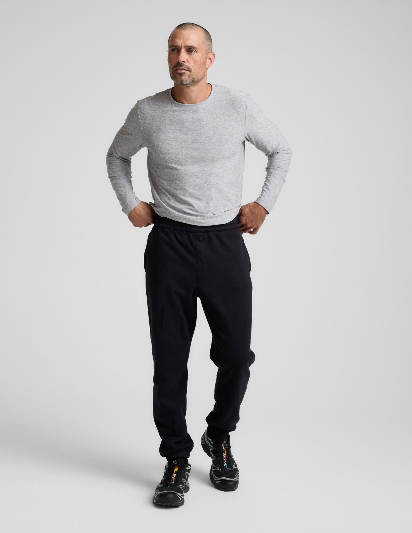 A man stands wearing black Classic Fleece Men's Jogger with a relaxed fit, elastic waistband, and gathered ankle cuffs.