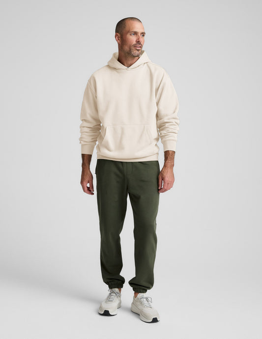 Man wearing Olive Classic Fleece Men's Jogger in a relaxed fit, paired with a cream hoodie and white sneakers.