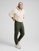 Man wearing Navy Classic Fleece Men’s Jogger™ in a relaxed fit, paired with a cream hoodie and white sneakers.