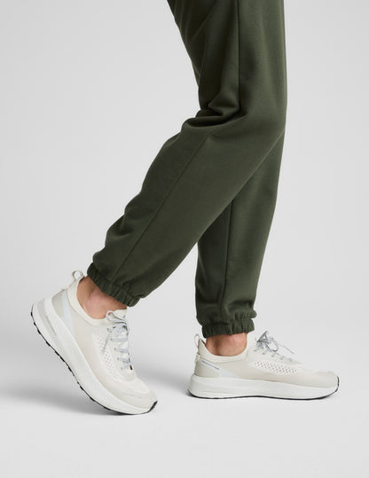 Side profile of man wearing Olive Classic Fleece Men's Jogger™ with elasticated cuffs, paired with cream sneakers.