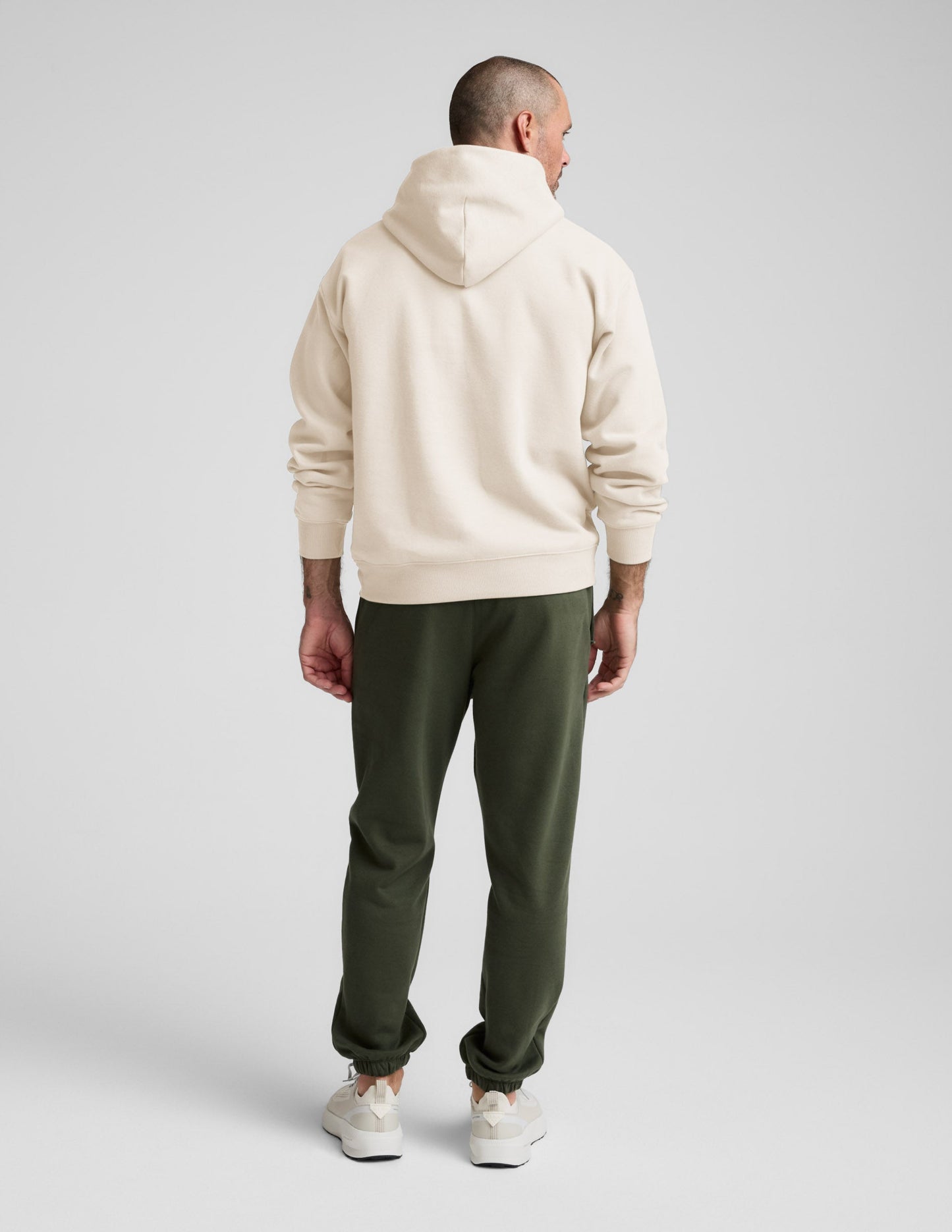 Rear view of man wearing Navy Classic Fleece Men's Jogger™ with a cream hoodie, featuring a relaxed fit and elasticated cuffs.