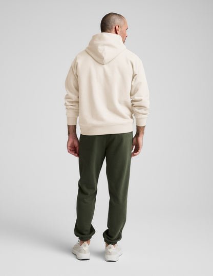 Rear view of man wearing Navy Classic Fleece Men's Jogger™ with a cream hoodie, featuring a relaxed fit and elasticated cuffs.
