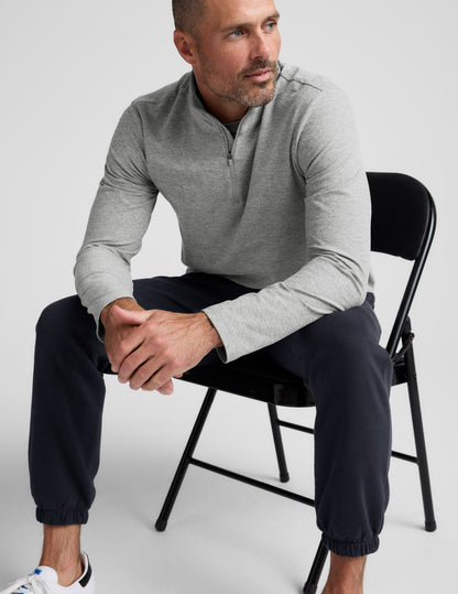 Man sitting on a chair wearing the dark Classic Fleece Men's Jogger with a relaxed fit and elasticated cuffs.