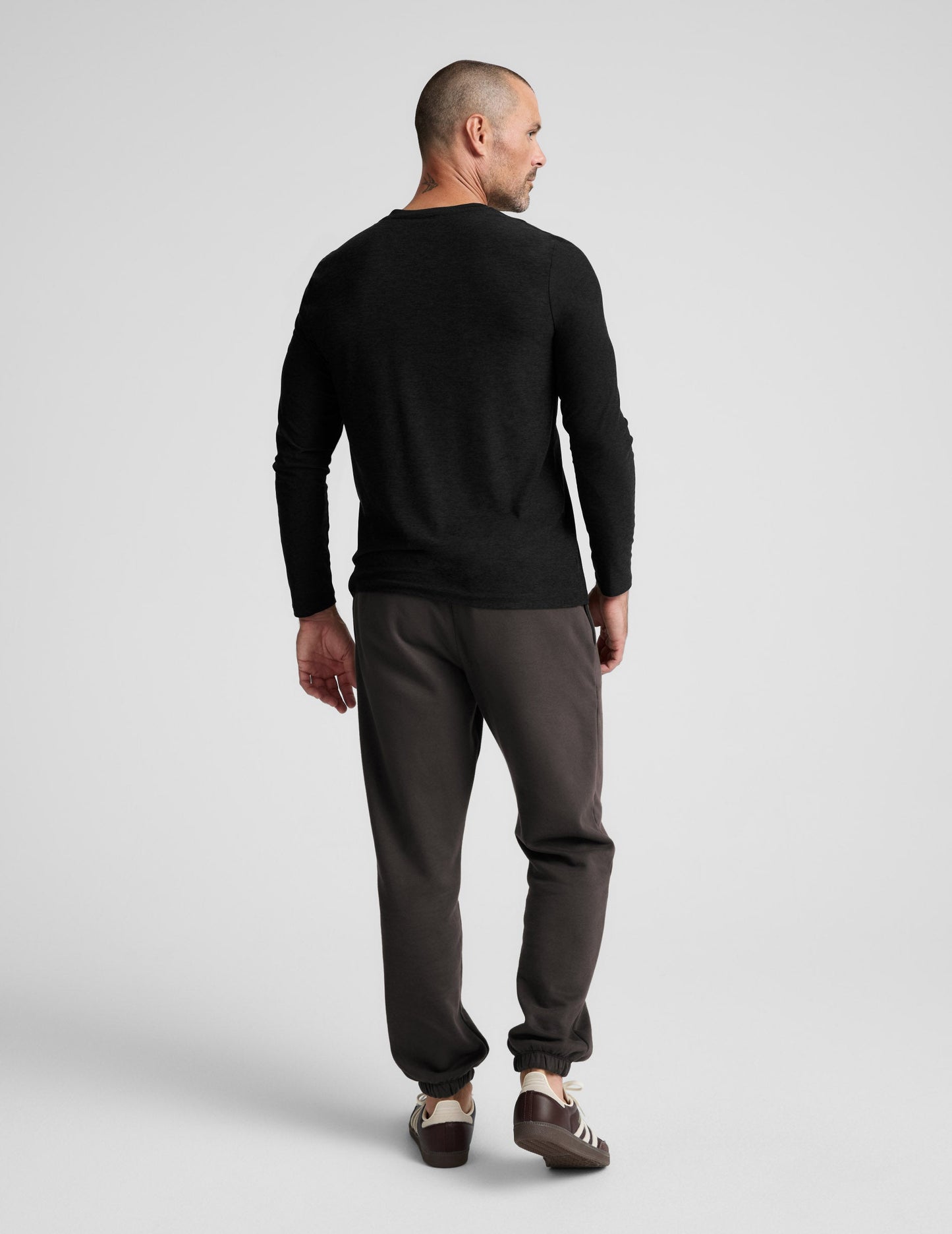 Rear view of a man wearing the dark Classic Fleece Men's Jogger featuring a relaxed fit and gathered elastic cuffs.