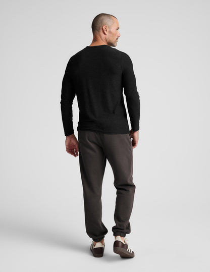 Rear view of a man wearing the dark Classic Fleece Men's Jogger featuring a relaxed fit and gathered elastic cuffs.