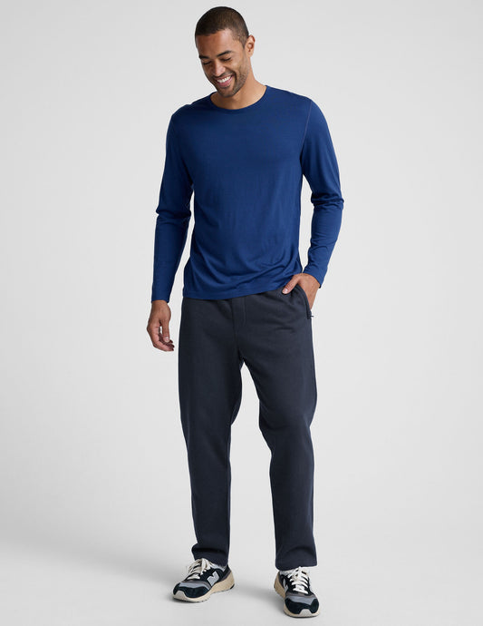 Man smiles in navy LuxeFleece Men's Straight Leg Pant, showing the relaxed straight fit and zippered side pockets.