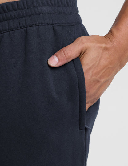 Close-up of navy LuxeFleece Men's Straight Leg Pant showing the elastic waistband and a hand in the side zippered pocket.
