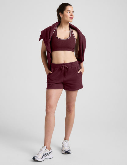 Maroon LuxeFleece Sweat Short on a woman posing with hands in pockets, featuring an elastic waistband and drawstring.