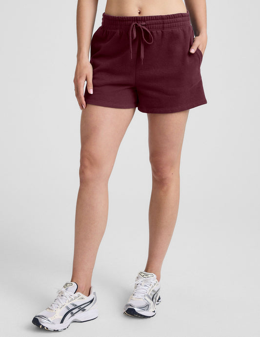Maroon LuxeFleece Sweat Short featuring an elastic drawstring waistband and side pockets, shown on a model.
